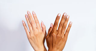 Two hands with different skin tones crossed to display neatly manicured nails